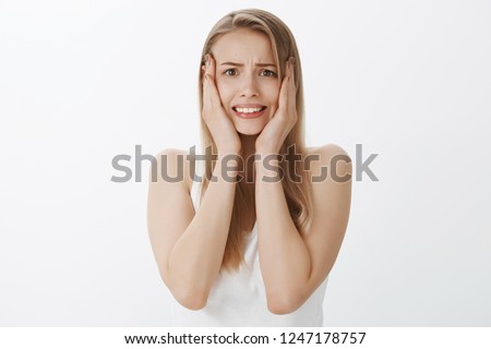 Yikes, got no time what shall I do. Portrait of worried overthinking and panicking cute girl with blond hair in tank-top clenching teeth grabbing head with hands and frowning as being under pressure Royalty-Free Stock Photo #1247178757