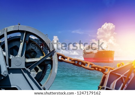 Big chain for Mooring winch, Mooring winch lass rope anchor at ship forward in shipyard of large with Big Chain and rusty with blue rope in drum and cargo ship sailing in the sea background.