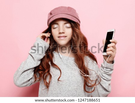 Joyful amazing little girl wearing pink  listening to music  with headphones isolated on pink background. Expressing brightful emotions to camera, enjoying lovely song. Lifestyle concept.
