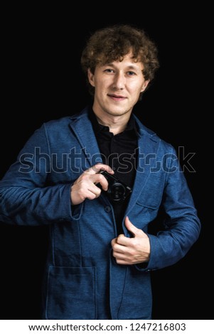 Man in jacket with camera looking at the camera on black background