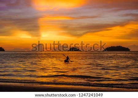 silhouette of man  kayaking on sea at beautiful sunset time