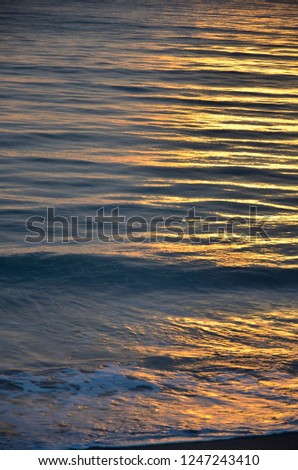 A golden scene of sunset reflection on the Haad Son beach, Khao Lak, Phang Nga, Thailand during summer time.