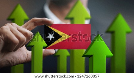 Nation Growth Concept, Green Up Arrows - Businessman Holding Card of East Timor Flag