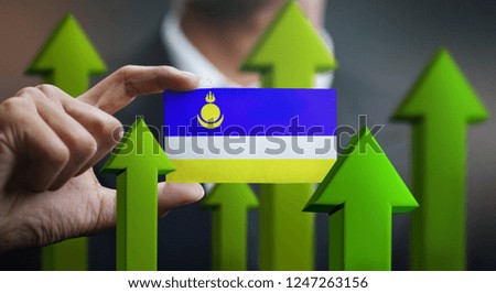 Nation Growth Concept, Green Up Arrows - Businessman Holding Card of Buryatia Flag 