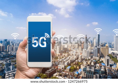 hand holding mobile smart phone with cityscape,5G network interface and wifi icon concept