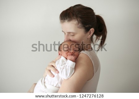 Gentle mother holds in her arms a sleeping newborn baby, innocence and trust.