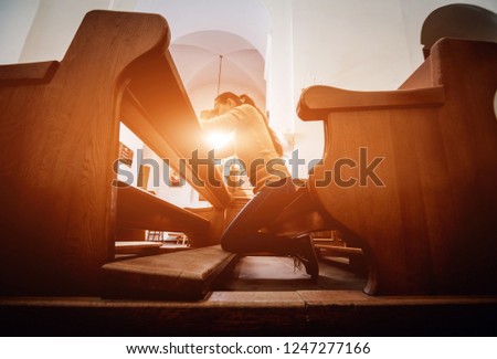 Christian woman praying in church. Hands crossed and Holy Bible on wooden desk. Background