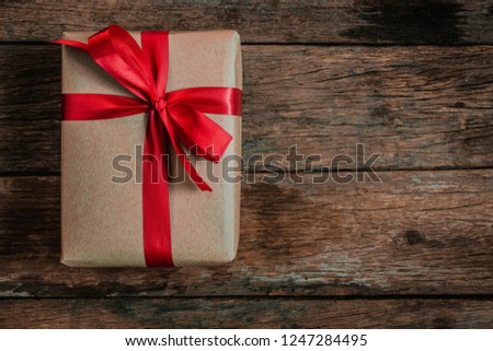 Brown Gift box bow tie Red ribbon On old wood floor top view merry christmas and happy new year concept