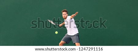 Tennis player man hitting ball with forehand hit on outdoor court playing game. Male sports athlete working out cardio traning. Panorama banner on green background.