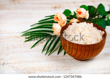 Wooden bowl with sea salt, rose and palm leaf. Spa accessories.