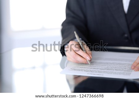Close-up of female hands with pen over document,  business concept. Lawyer or business woman at work in office