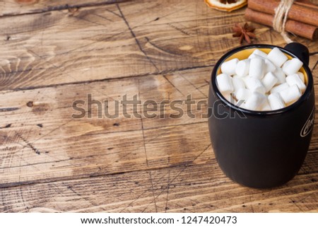 Hot chocolate with marshmallow cinnamon sticks, anise, nuts on wooden background, Christmas concept.