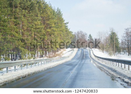 Melting snow outside of the city on the country road. Weather forecast for early spring. Melting snow, difficult road. Early spring in temperate climate. Spring is coming. Sunny spring weather