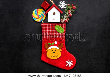 Christmas gift concept, christmas surprises. Traditional festive socks filled with gift box, sweets, winter decor on black background top view copy space