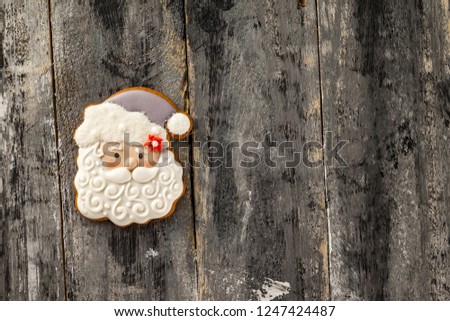 Top view image of gingerbread Santa Claus iced cookie at vintage hardwood board background.