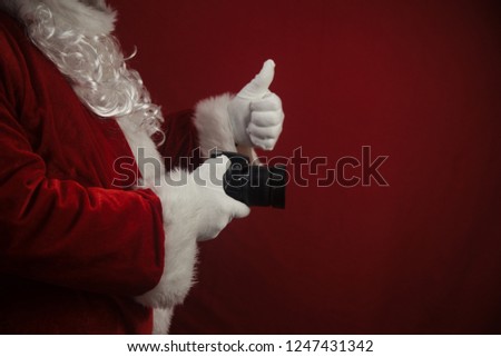 Santa Claus using DSLR camera taking images showing thumb up. Happy Christmas Evening and New Year celebration background. Fun loving creative costume time