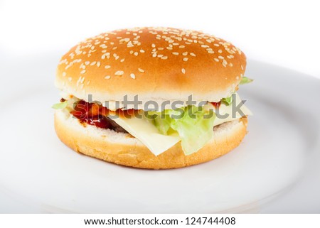 Delicious juicy cheeseburger with tomato and lettuce on a plate on white background