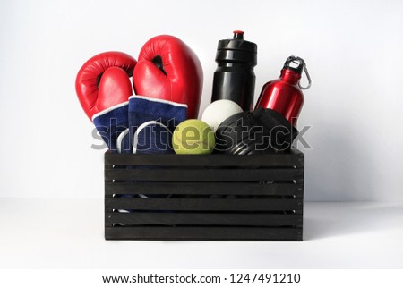 different sports items in the box: boxing gloves, dance shoes, racquets and tennis balls, water bottles. concept of healthy lifestyle