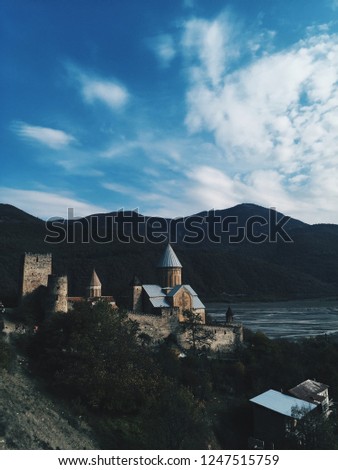Ananuri fortress in Georgia at sunset with silhouette of mountains at background