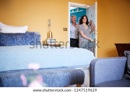 Middle aged couple arrive at a hotel room, smiling