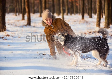 boy playing with husky in winter park
