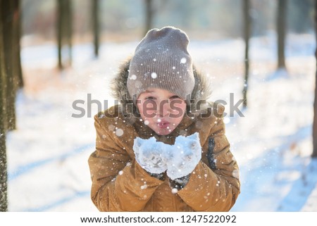 boy in a warm jacket, hat and gloves in the winter park

