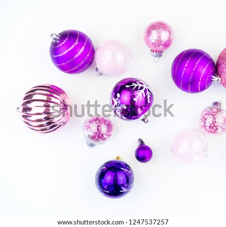 Gentle pink and purple baubles on a white background. Christmas mood. Festive decor. Sequins and glitter for a party.