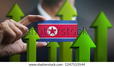 Nation Growth Concept, Green Up Arrows - Businessman Holding Card of North Korea Flag 