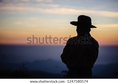 Portrait of a man wearing a hat Looking at the mountains in the evening.