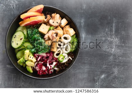 Vegan bowl with guinoa, vegetables and tofu on dark background with copy space