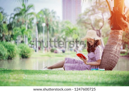 Education outdoor, Portrait of young woman smiling is reading a book in the park.