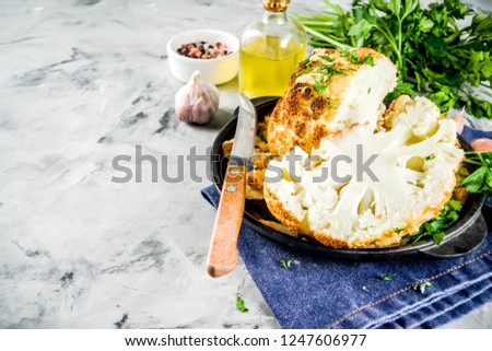 Homemade Whole Roasted Cauliflower in a Skillet, with olive oil and herbs. grey stone or marble background copy space