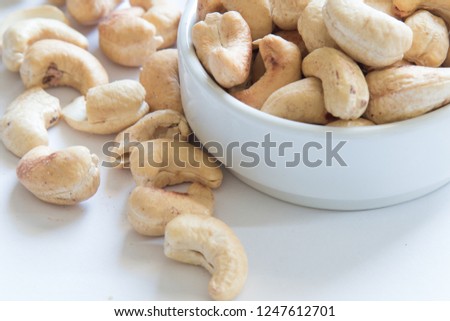 roasted cashew nuts on a ceramic bowl and white background