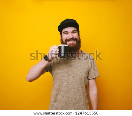 Happy and cheerful bearded hipster man drinking tea or coffee over yellow background Royalty-Free Stock Photo #1247613550