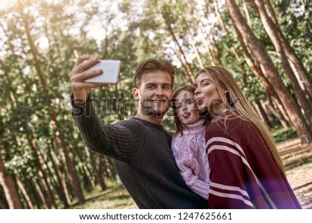 Happy family taking selfie by smartphone in woods