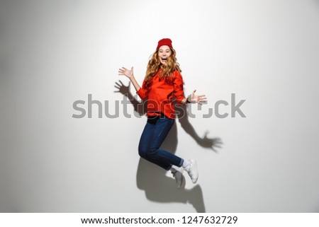 Full length photo of brunette woman 20s wearing red clothes laughing while jumping isolated over white background