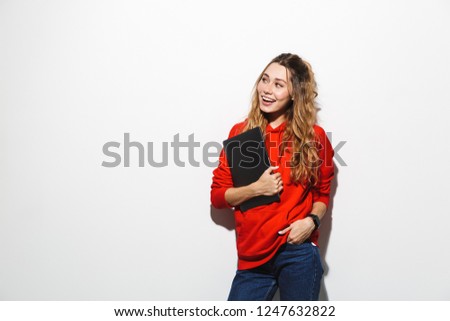 Image of adorable woman 20s wearing red sweatshirt holding gray laptop isolated over white background