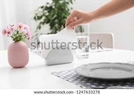 Woman taking paper tissue from ceramic napkin holder on served table Royalty-Free Stock Photo #1247633278