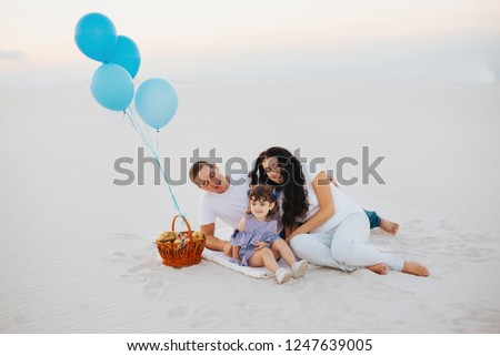 Family sitting on sand With Picnic Basket . family with balloons