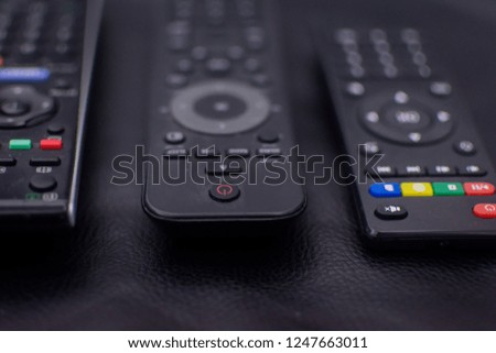 three old remote controls, photography with a slight blur, on a black background.