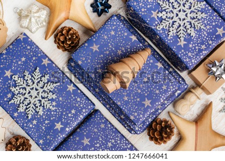 Creative chritmas composition. Presents in blue wrapping paper with silver sparkles, wooden decorations, ornaments on white table, top view, selective focus