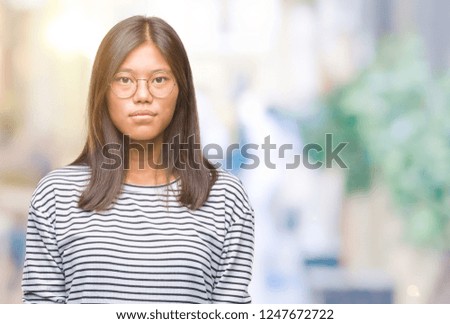 Young asian woman wearing glasses over isolated background with serious expression on face. Simple and natural looking at the camera.