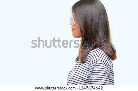Young asian woman wearing glasses over isolated background looking to side, relax profile pose with natural face with confident smile.