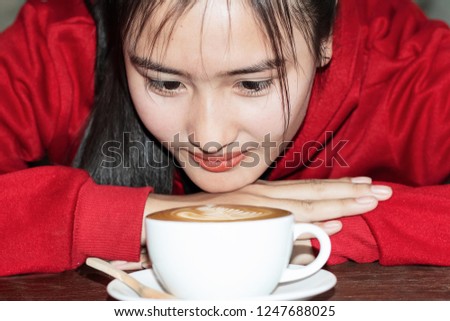 Closeup image of Asian young girl smelling and drinking hot coffee with feeling good in cafe