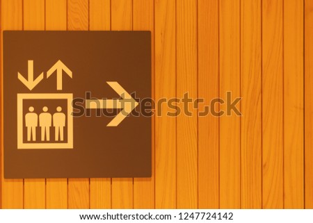 Building direction sign banner label arrow way to lift elevator on wood background.