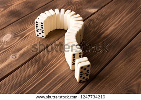 Domino question mark on wooden table. Domino principle.