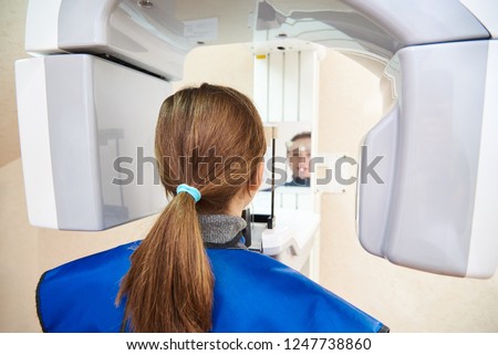 A patient in a protective suit is standing next to the device. Computer diagnostics. dental tomography Royalty-Free Stock Photo #1247738860