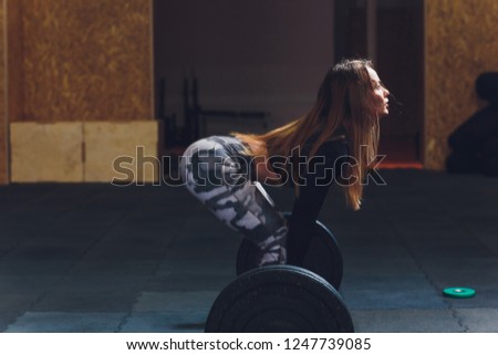 Attractive young sports woman with barbell. Deadlift.