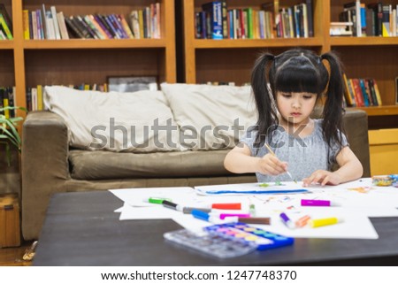 Asian girl kid doing drawing with many colour pencils on white paper over white background