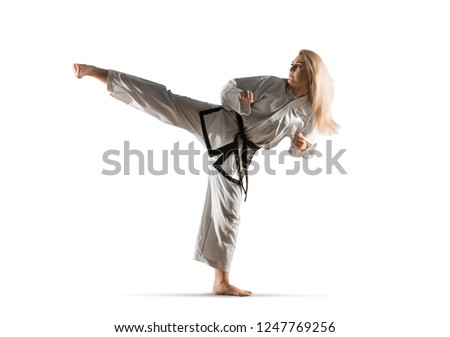 Woman in kimono practicing taekwondo. Isolated on white background Royalty-Free Stock Photo #1247769256